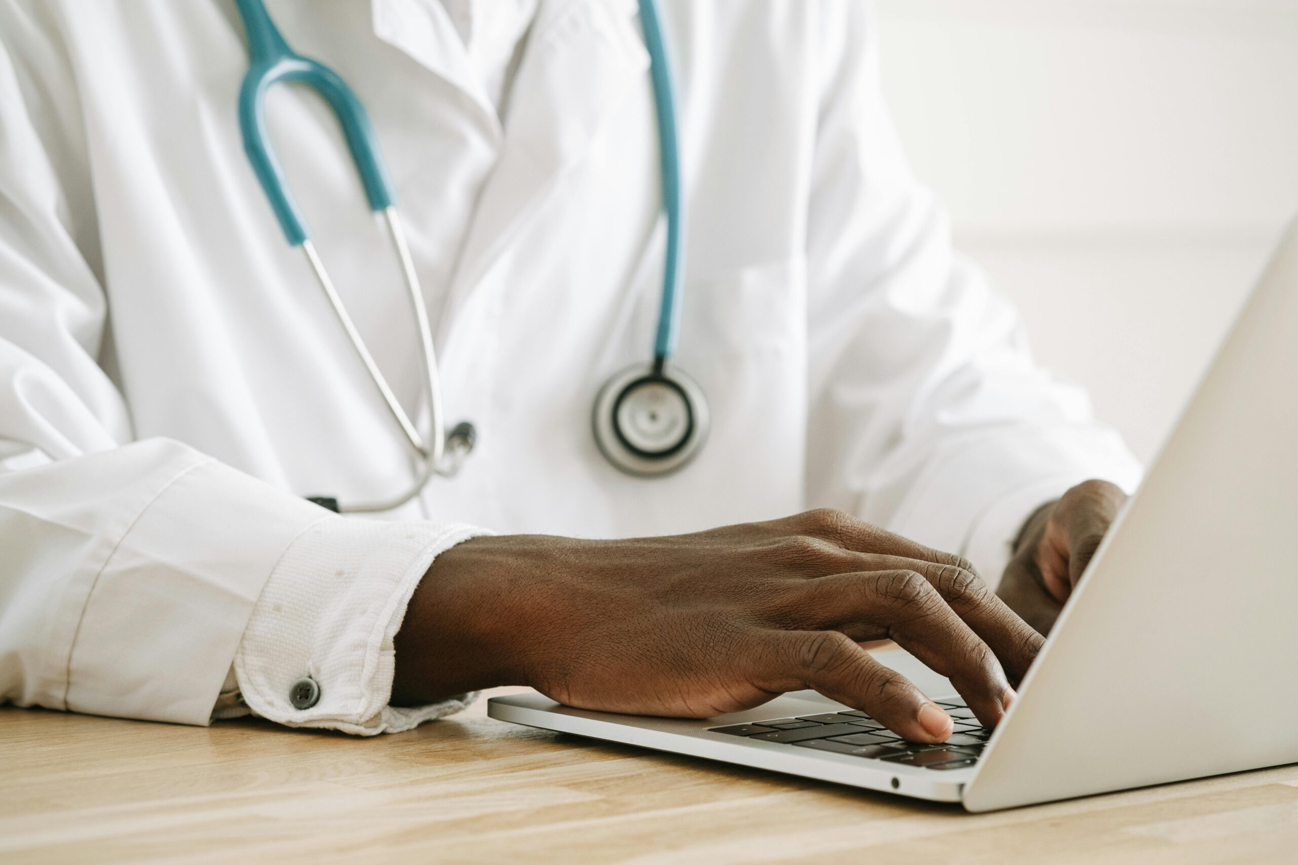 Black healthcare professional typing on a laptop with a stethoscope — symbolizing diversity in kidney research through the Kidney Foundation’s KRESCENT program.