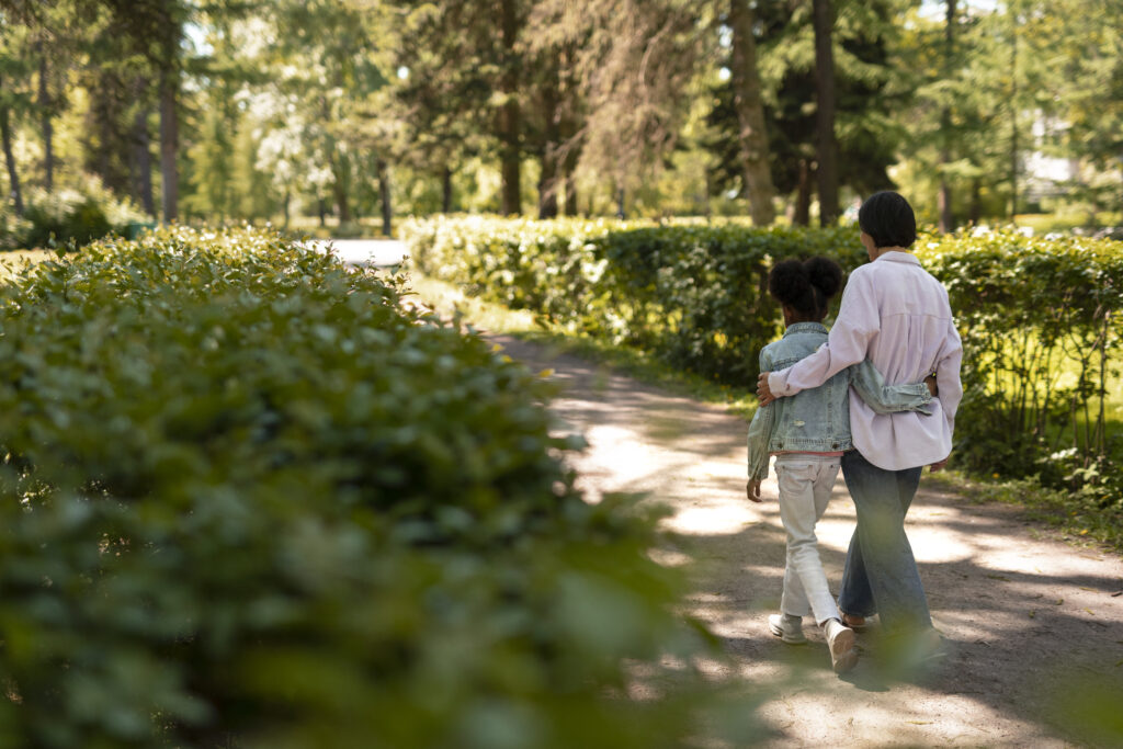 Mother and daughter walking together through a green park in British Columbia, representing local charities promoting family wellness and outdoor mental health programs.