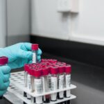 Gloved technician handling blood sample tubes in a laboratory for liquid biopsy testing.