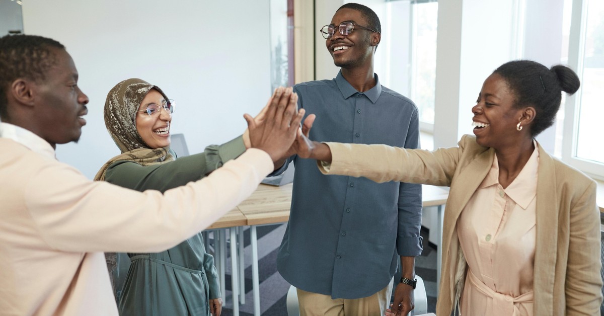 Diverse group of adults smiling and high-fiving during a supportive community meeting in Quebec