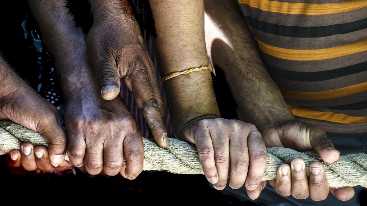 men of different races hands holding rope.