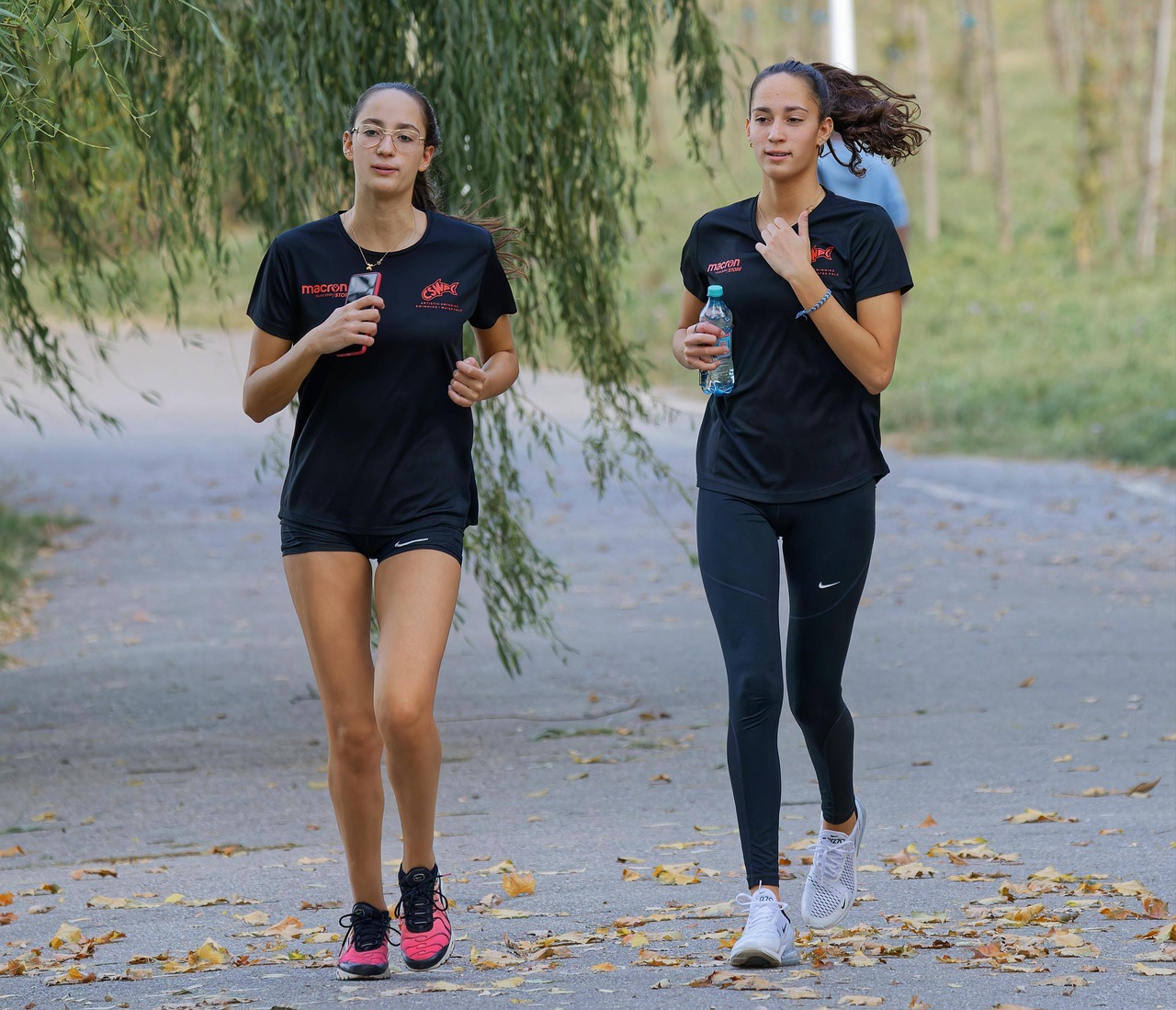 Two women running outdoors with water bottles in their hand