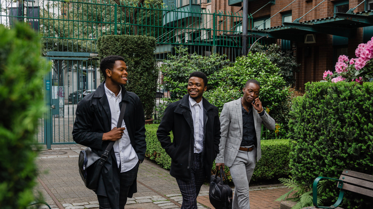 Three Black young professionals walking through an urban courtyard, highlighting youth leadership and career development in Canada.