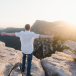 Person standing on a mountain overlook at sunrise, symbolizing hope, recovery, and a fresh start after addiction treatment.