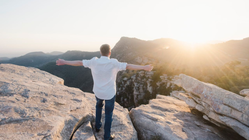Person standing on a mountain overlook at sunrise, symbolizing hope, recovery, and a fresh start after addiction treatment.