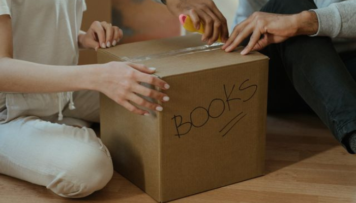 People packing a box of books for donation to a Canadian charity, supporting literacy, education and community programs.