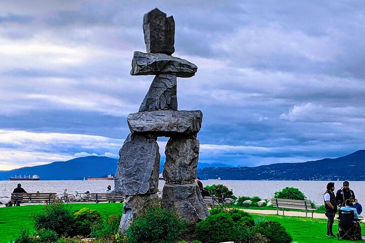 Inukshuk monument overlooking English Bay with mountains in the background in Vancouver, British Columbia.