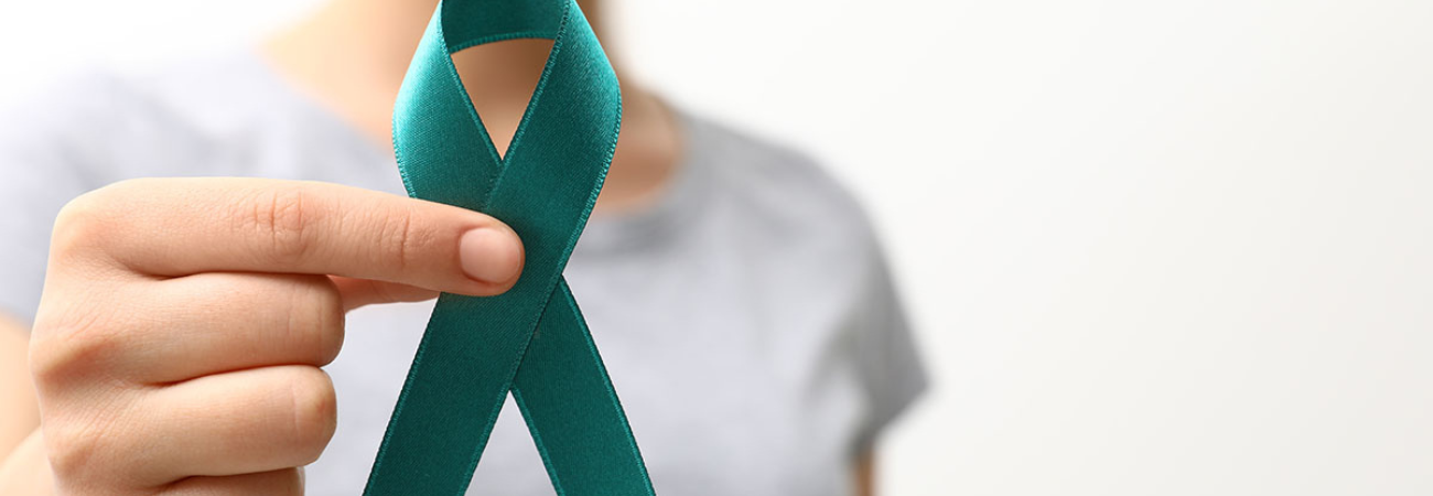 Personne tenant un ruban sarcelle, symbole de sensibilisation au cancer de l'ovaire.
